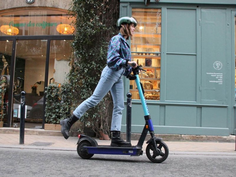 Eine junge Frau fährt in der Innenstadt mit einem E-Scooter.